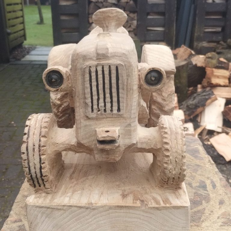 Holzskulptur eines Traktors mit zwei Rädern und detailliertem Kühlergrill.